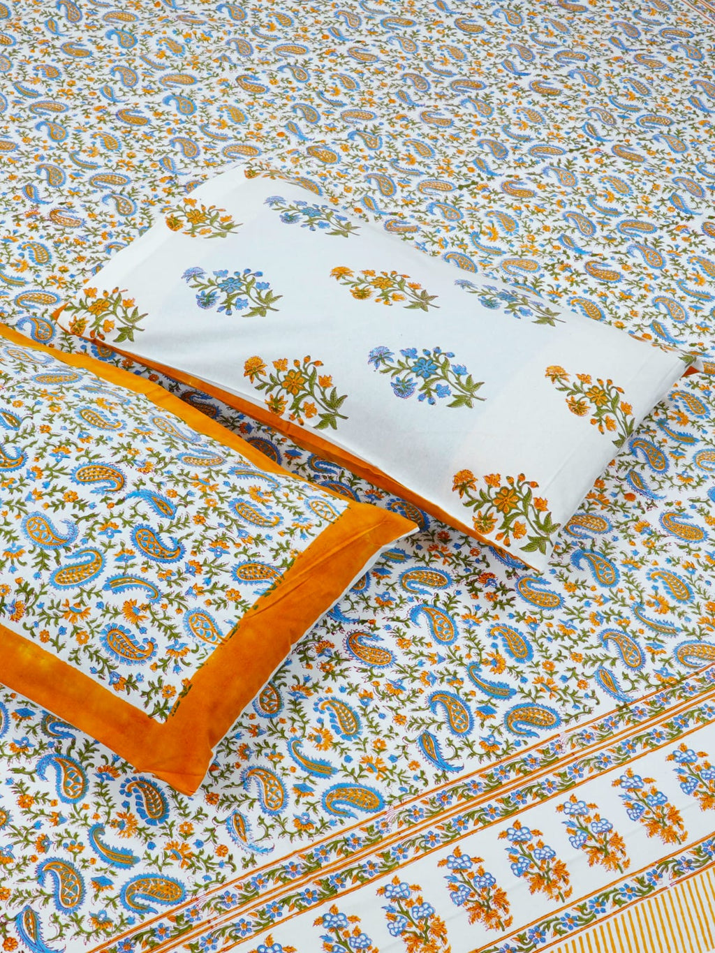 Floral and paisley patterned bedspread with a pillow on a matching background