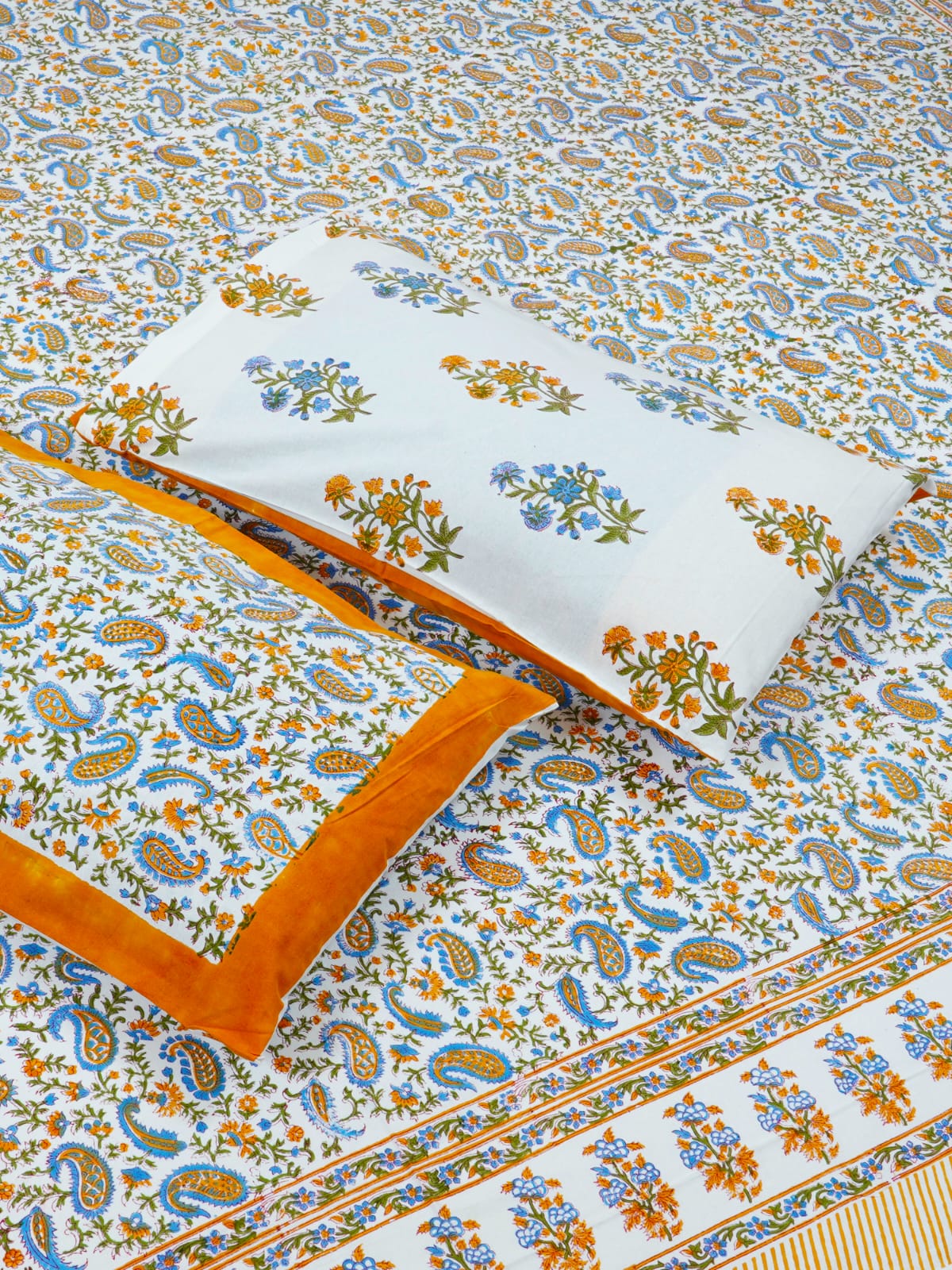 Floral and paisley patterned bedspread with a pillow on a matching background