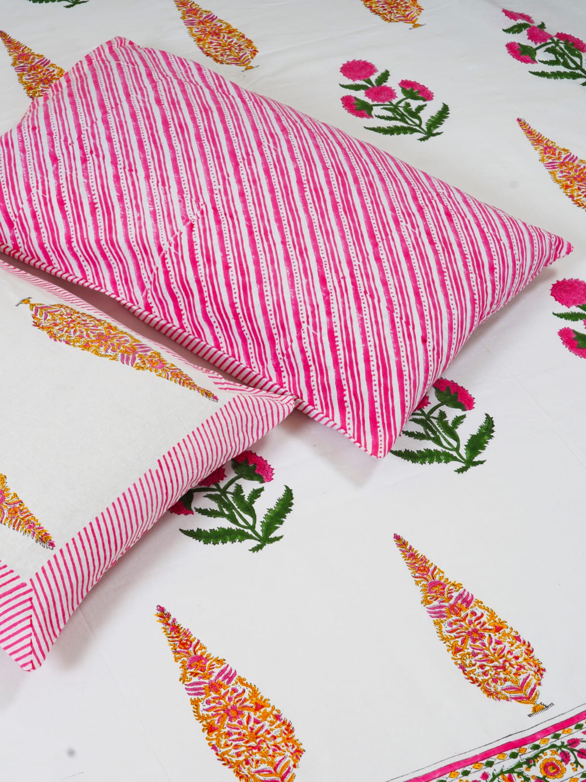 mugal butta printed bedsheet,Pink striped pillow on a fabric surface with colorful patterns